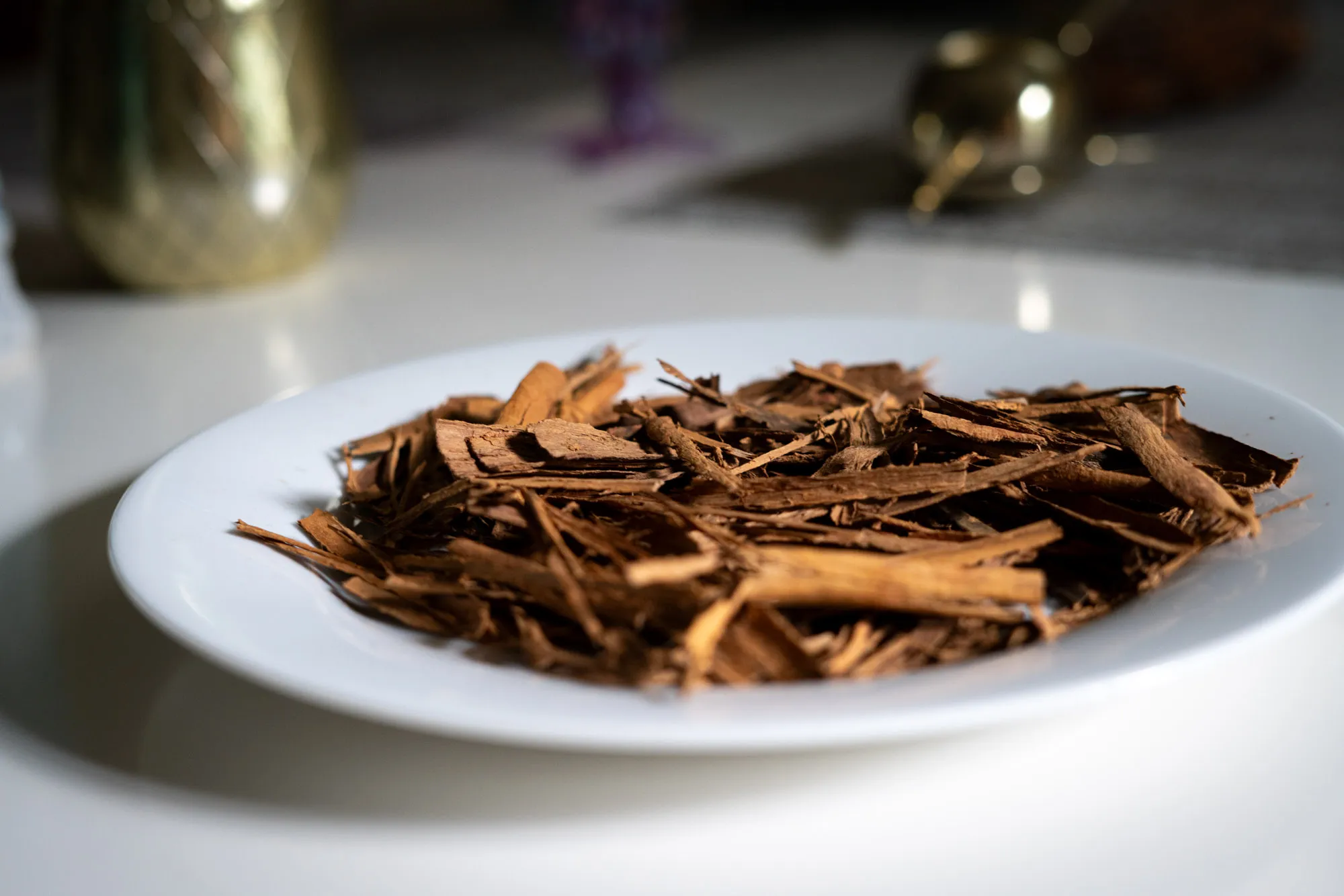 A white plate piled with shards of cinnamon bark