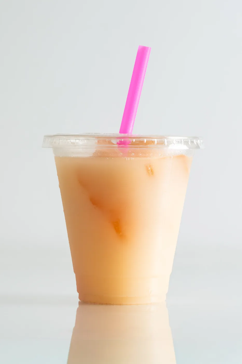 A clear plastic to-go cup of horchata cocktail with a bright pink straw.