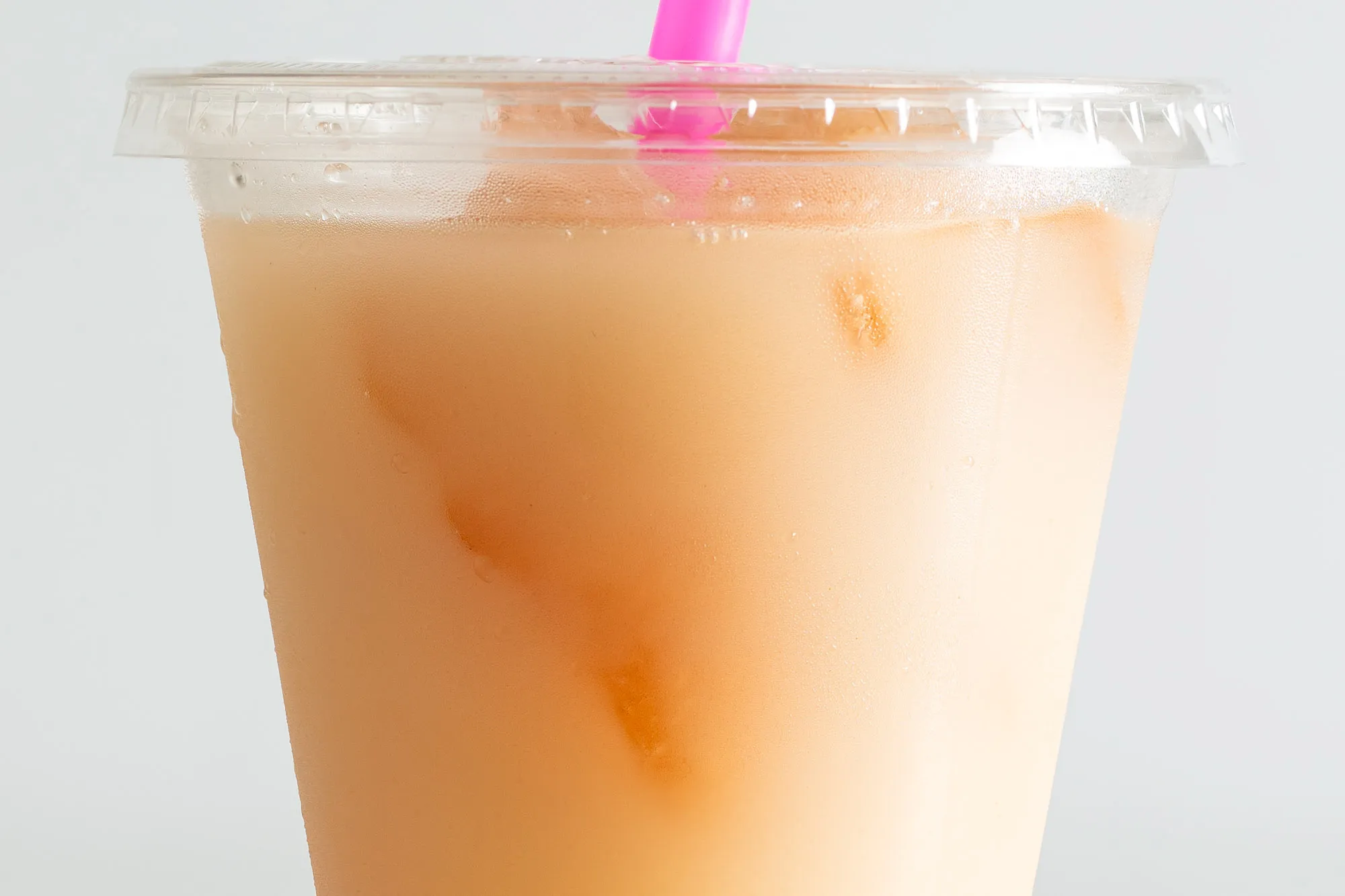 Close-up of the horchata cocktail in a to-go cup, with chunks of cinnamon ice visible through the plastic