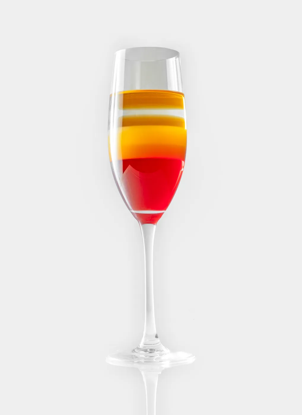 A layered red, orange, and yellow Hurricane cocktail in a champagne flute
